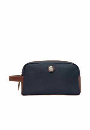 Rechteckige navyblaue Kulturtasche mit braunen Lederakzenten, Reißverschluss, seitlichem Griff und rundem metallischem Logo vorne in der Mitte.