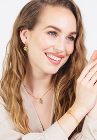 Gouden sieraden set met ronde oorbellen, een delicate ketting en een bijpassende armband, allemaal met gladde oppervlakken en een minimalistisch ontwerp.