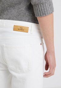 Vita denimjeans med en läderpatch märkt "WON HUNDRED" på den bakre midjebanden. Har standard bakfickor och en figurnära design.