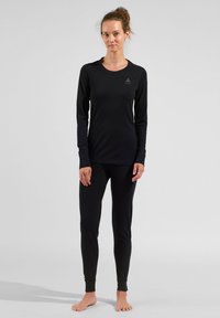 Black long-sleeve top and matching leggings made of a smooth, stretchy fabric. Features a round neckline and logo detail on the chest.