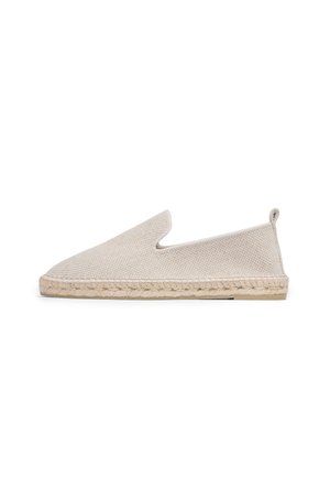 Beige canvas slip-on shoe with a woven jute sole. Features a smooth texture, rounded toe, and a discreet rear pull tab.