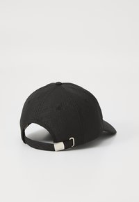 Black cap made of textured fabric, featuring a subtle geometric pattern. Adjustable strap at the back with a metal buckle.