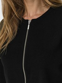 Maglione nero con scollo rotondo e una cerniera argento a tutta lunghezza, caratterizzato da una texture morbida e una silhouette aderente.