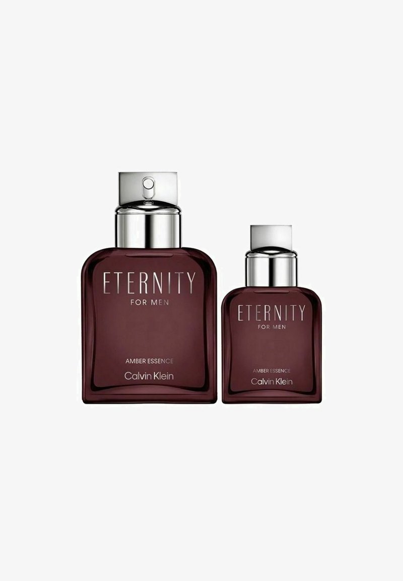 Kaksi tummaammberista lasipullosta parfyymejä hopeakorkeilla, joissa on etiketit "ETERNITY FOR MEN" ja "AMBER ESSENCE".