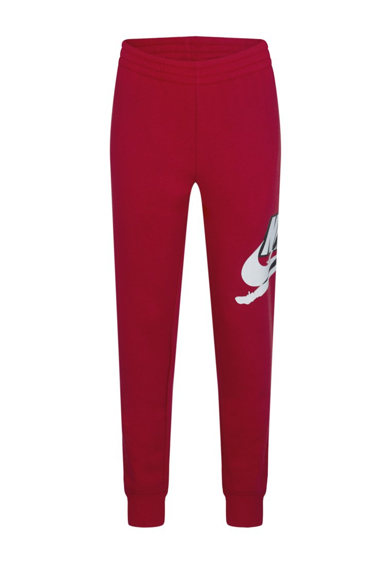 Pantalons de survêtement Nike rouges avec une taille élastique et des poignets, présentant un grand logo swoosh Nike blanc et noir sur la cuisse gauche.