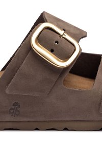Bruine suede sandaal met uitsnijdingen aan de zijkanten, grote gouden metalen gesp, getextureerde binnenzool en gebossed logo aan de buitenzijde. Rubberen zool.