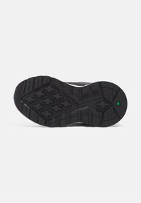 Black rubber shoe sole with textured tread pattern for traction. Features a green accent near the heel and a smooth edge design.