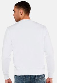Felpa bianca, colletto a giro, maniche lunghe, polsini e orlo a coste, texture morbida, design minimalista, mostrata da dietro.