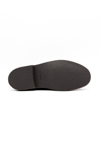 Semelle de chaussure en caoutchouc noir avec une surface texturée, un bout arrondi et un léger talon. Présente le nom de la marque embossé "Clarks" près de la zone du talon.