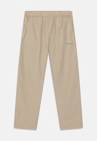 Beżowe spodnie z elastycznym paskiem w pasie, z bocznymi kieszeniami, w luźnym kroju i niebieskim haftem na tylnej kieszeni. Miękka tekstura materiału.