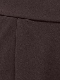 Gros plan sur un tissu marron foncé avec un détail de couture et de pli, montrant la texture et les coutures sur un vêtement.