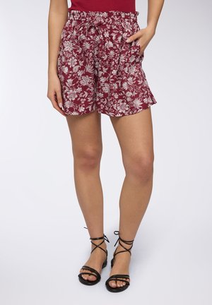 Bordowe szorty w kwiaty z elastycznym pasem, sznurkiem do regulacji i bocznymi kieszeniami. Wzór przedstawia białe kwiaty na strukturalnym materiale.