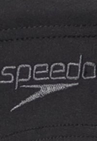 Tissu noir avec le logo "Speedo" en broderie grise, avec un design aérodynamique et une texture lisse.