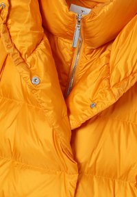 Chaqueta acolchada amarilla con collar alto, cierre de cremallera plateada y textura acolchada. Incluye detalles de botones a presión y un acabado brillante.