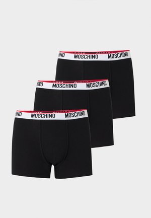 Tre boxer neri con fascia in vita bianca con il nome del marchio Moschino in lettere nere e un bordo interno rosso.