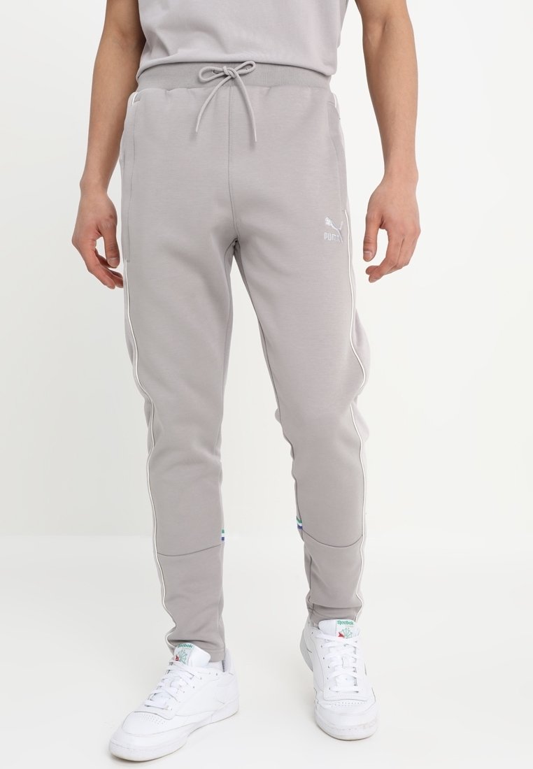 Pantalones joggers de color gris claro hechos de tela suave, con cintura ajustable con cordón, bolsillos laterales y detalles blancos a lo largo de las costuras.
