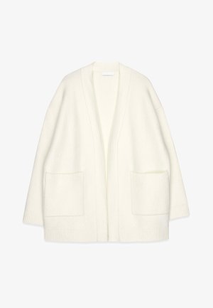 Baltas vilnas kardigans ar brīvu piegriezumu, atvērta priekšpuses, ribota apakšdelma daļa un divas priekšējās kabatas. Tekstūrēta auduma ar mīkstu apdari.