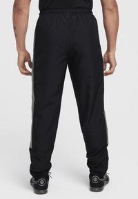 Schwarze Sporthosen mit einem gerafften Bund, die graue Seitenstreifen und elastische Bündchen an den Knöcheln haben. Glattes, leichtes Material.