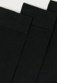 Black cotton socks with a ribbed texture and elasticized cuffs. Three pairs stacked with visible seams and smooth finish.