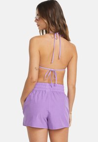 Violetter Halter-Bikini mit verstellbaren Bindeträgern und passenden violetten Shorts mit elastischem Bund und weicher Stofftextur.