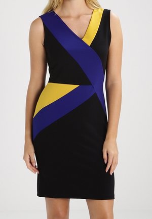 Černé šaty bez rukávů s výstřihem do V a výraznými diagonálními žlutými a modrými geometrickými pruhy přes přední část a pás.