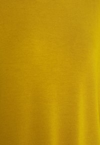 Tissu jaune avec une texture lisse, présentant une couleur uniforme sans motifs ni accents. Le matériau semble doux et léger.