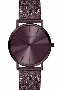 Rund klocka med en borstad metallisk lila urtavla och tunna timmarkörer, med ett strukturerat lila armband prytt med glittrande detaljer.