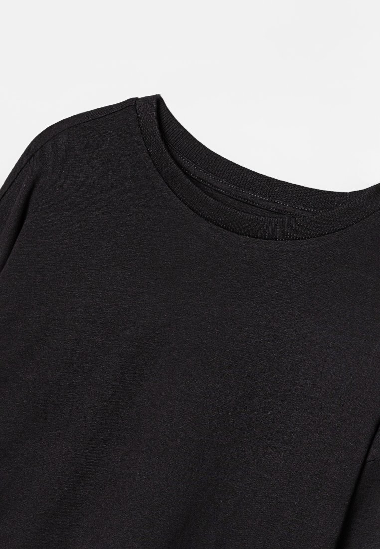 Schwarzes T-Shirt mit kurzen Ärmeln und rundem Halsausschnitt. Hergestellt aus glattem Baumwollstoff, mit sauberen Nähten und klassischer Passform. Ohne Muster oder Akzente.