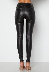 Černé skinny džíny z umělé kůže s těsným střihem, vysokým pasem a dvěma zadními kapsami. Hladký povrch a vysoký lesk.
