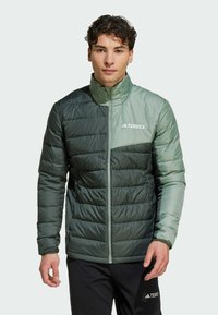 Giacca isolante verde con design trapuntato, dotata di colletto alto e zip parziale. Logo Terrex sul lato superiore sinistro.