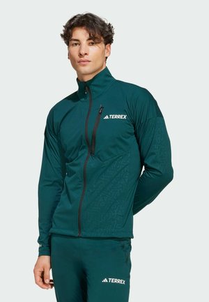 Teal jack met rits aan de voorkant, hoge kraag, zijzakken en een gestructureerd patroon op de mouwen. Voorzien van het "TERREX"-logo op de borst.