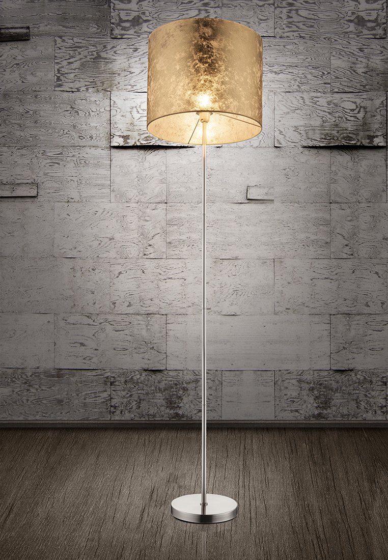Stehlampe mit einem metallisch silbernen Fuß und schlankem Rohr, gekrönt von einem goldfarbenen, strukturierten zylindrischen Schirm, der Licht abgibt.