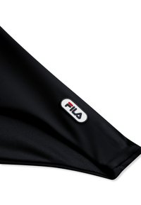 Article en tissu noir avec un logo ovale FILA blanc, lettres rouges et noires, sur un coin plié.