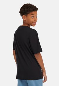 Zwarte katoenen T-shirt met korte mouwen, ronde hals en een ontspannen pasvorm, gezien vanaf de achterkant met een gladde textuur.
