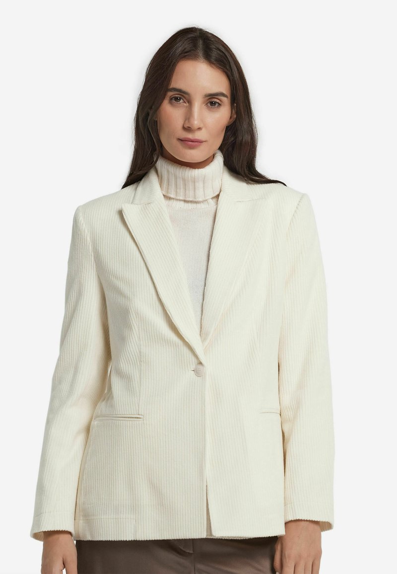 Cremefarbener Cordblazer mit Reverskragen, einreihigem Knopfverschluss, Klappentaschen und strukturiertem Schnitt. Glatte Textur, zeitloses Design.
