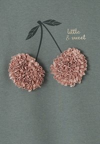 Grauer Stoff mit einem plüschigen, rosa Kirsch-Applikation, die geschichtete Blütenblätter zeigt, ergänzt durch schwarze Stiele und grüne Blätter. "little & sweet" in Gold gedruckt.