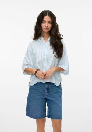 Lys blå og hvit vertikalt stripet oversized skjorte med korte ermer, kombinert med høyt liv blå denimshorts. Struktureret stoff.