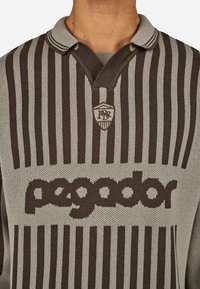 Pletené polo tričko v sivej a hnedej farbe s vertikálnymi pruhmi, s výstrihom do V, s nášivkou loga a menom "pagador" v veľkých písmenách.
