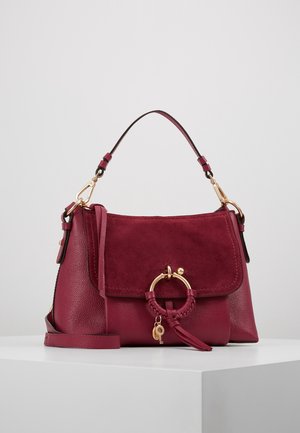 Bordeauxrode leren en suède handtas met gouden ring- en sleutelhanger, korte handgreep en afneembare schouderriem op een witte ondergrond.