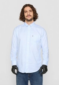 Svetlo modra srajca s karo vzorcem, z gumbi in dolgimi rokavi, iz bombažnega materiala, z majhnim izvezenim logotipom na levem prsnem žepu.