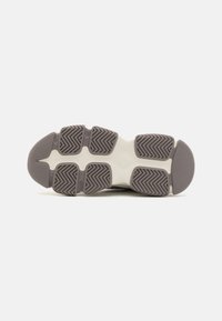 Sneaker outsole in gray and off-white rubber; features zigzag tread pattern and rounded toe. Smooth texture with pronounced grip sections.