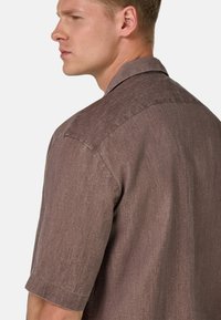 Camicetta a maniche corte con colletto in un misto lino scuro e testurizzato, caratterizzata da una vestibilità casual e dettagli di cucitura sottili.
