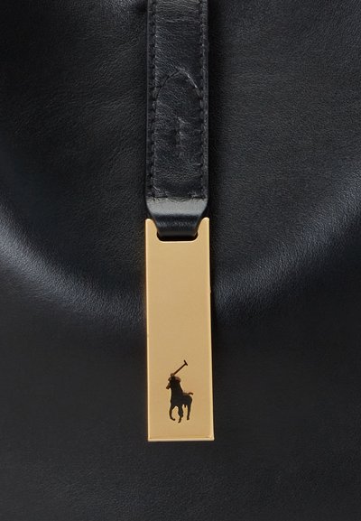 Bolso de piel negra con una textura suave, que presenta una etiqueta rectangular dorada grabada con un diseño en silueta de un jinete.