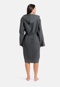 Šedý károvaný plášť s dlouhými rukávy a páskem, vyrobený z měkkého materiálu, s texturovanou kapucí a délkou po kolena.