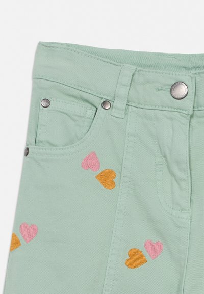 Lysegrønne bukser med sølvfarget knapp og nagler, dekorert med små rosa og oransje broderte hjerter nær lommene.