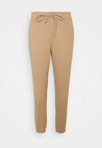 Beżowe dresowe spodnie z elastycznym pasem i sznurkiem, zwężane u dołu, o miękkiej fakturze, zaprojektowane z myślą o komforcie i codziennym noszeniu.