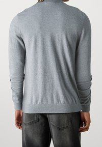 Maglione grigio aderente in maglia con maniche lunghe e colletto e orlo a coste. Texture liscia; vista posteriore che mostra una copertura completa e dettagli delle cuciture.