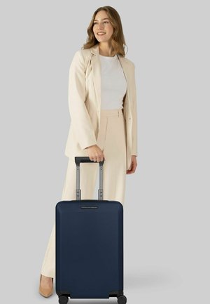 Marineblaue Hartschalen-Reisetasche mit glatter Textur, ausziehbarem Griff und vier Rädern. Mit einem Markenlogo auf der Vorderseite.