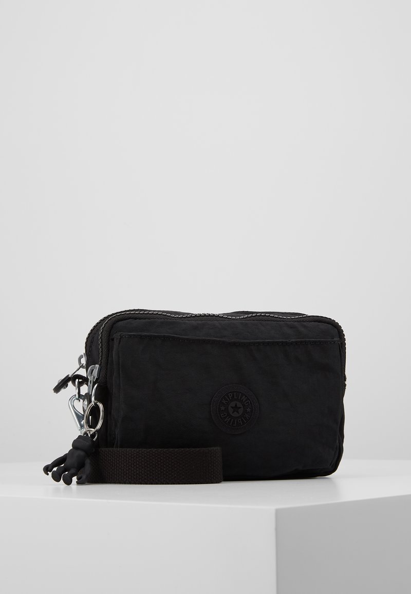 Zwarte nylon tas met ritssluiting, voorzien van een rond logo, een kleine aap hangertje en een afneembare bruine band voor gemakkelijk dragen.