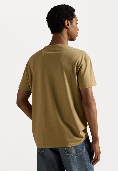 Camiseta de algodón color caqui con cuello redondo, mangas cortas y corte relajado, exhibida desde atrás con una textura suave.